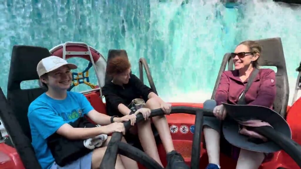 Riders enjoy a thrilling ride at an amusement park with a waterfall in the background.