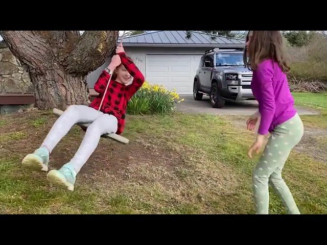 A person enjoying a makeshift tree swing in the backyard.