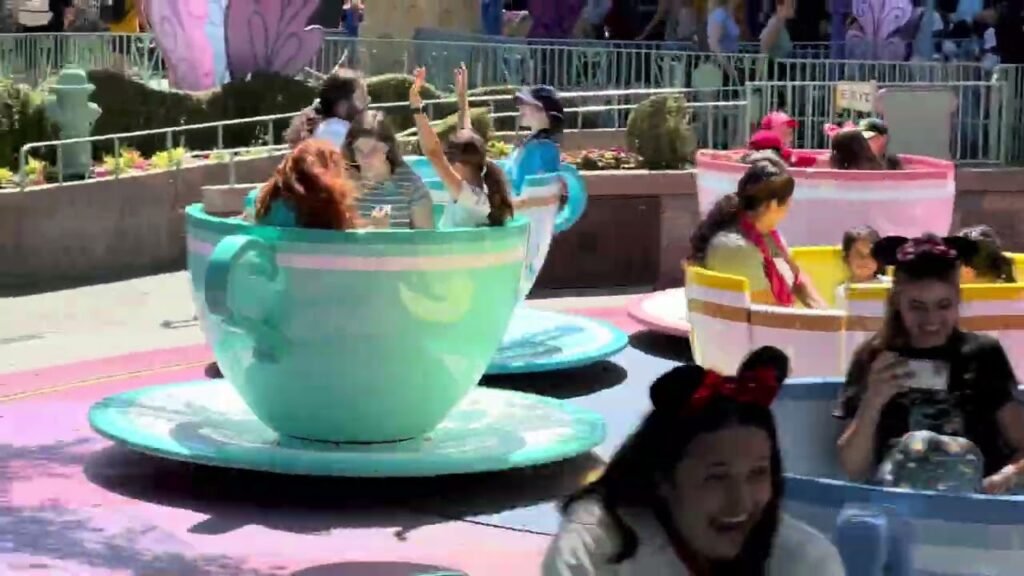 Families enjoying a ride in colorful teacups at a theme park.