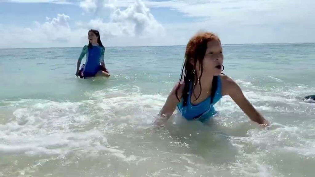 Two people swimming and playing in the ocean waves on a sunny day.