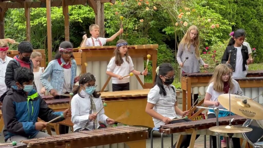 Group of young people playing set of large marimbas on stage outdoor