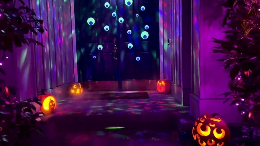 Brightly lit jack-o-lanterns glow ominously against a backdrop of vivid purple and blue laser lights at a Halloween event.