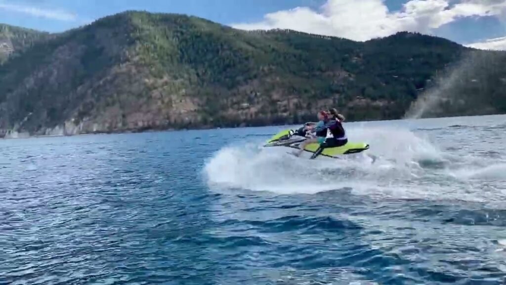 A person rides a jet ski through the blue waters of a fjord in the Pacific Northwest.