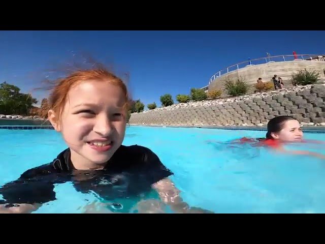 Enjoying a sunny day in a coastal swimming pool near a rocky breakwater. A fun summer memory by the water.