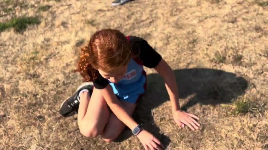 A person crouched in a grassy field.