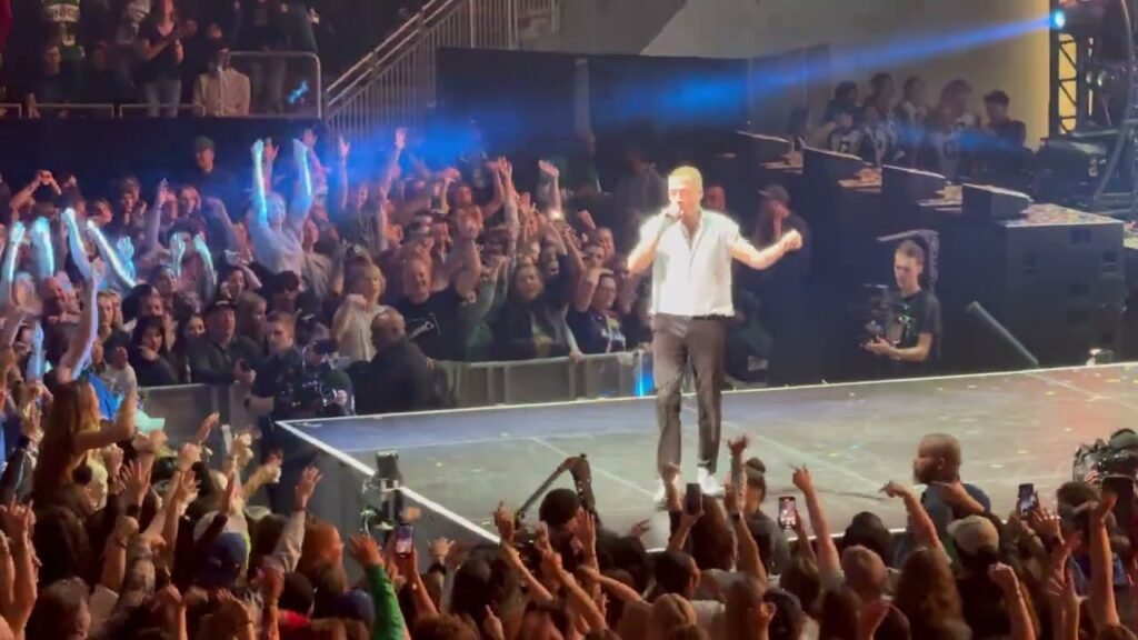 Performers pay tribute to Layne Staley on stage during a concert at Seattle Center, surrounded by a cheering crowd.