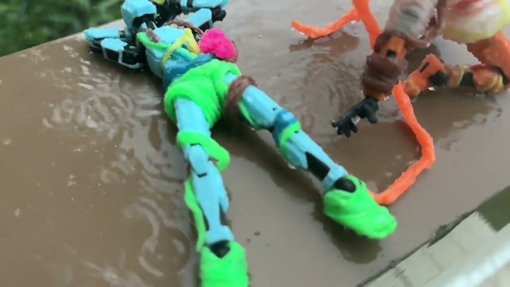 Brightly colored action figures, including a green and blue figure, lying on a wet brown surface.
