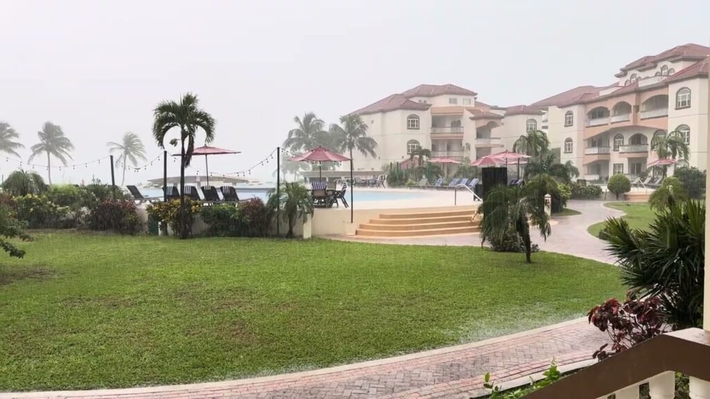 A stunning view of the resort grounds featuring lush green lawns, tall palm trees, and a swimming pool area in the distance.