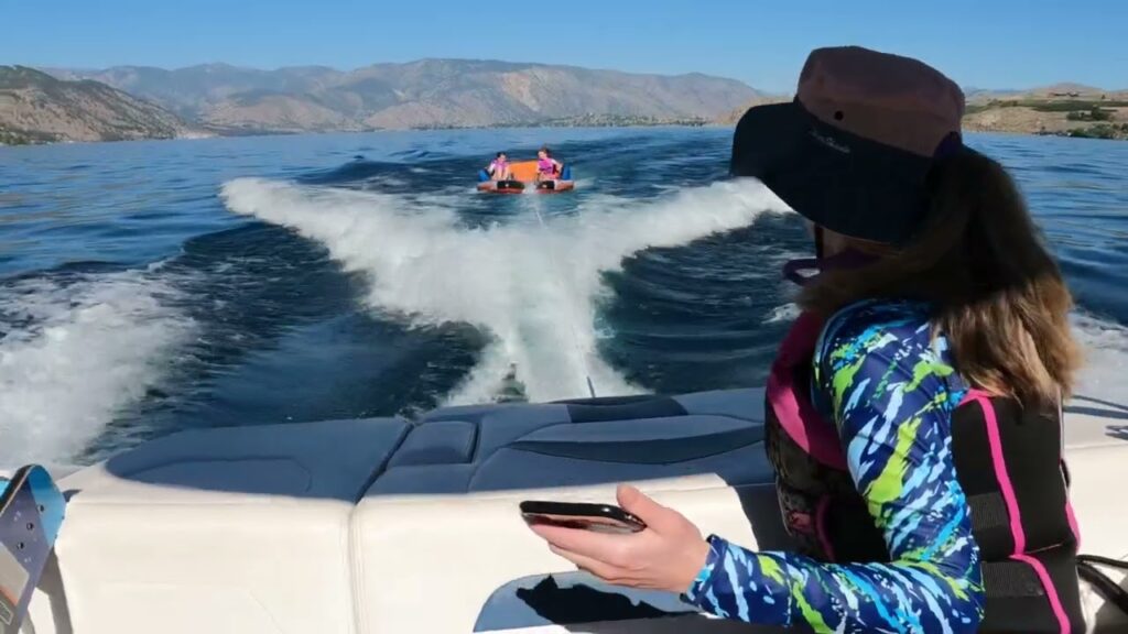 Person looking out over a lake at a jet ski leaving a foamy wake.