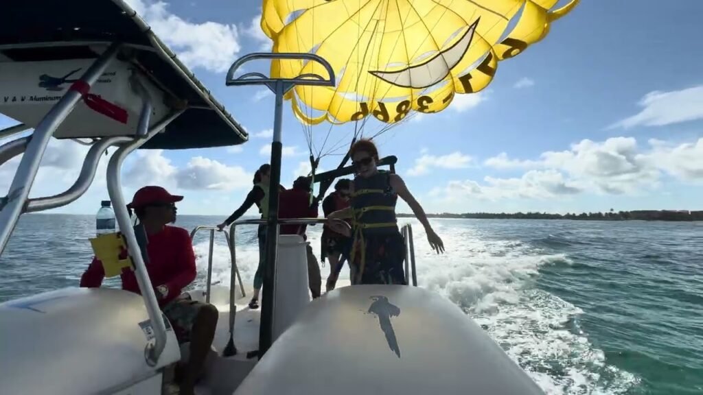 Group parasailing from a boat in the ocean under a bright yellow canopy.