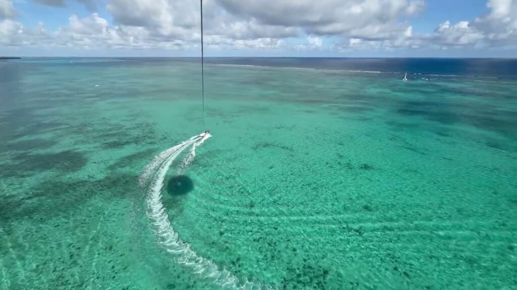 Aerial photo of a small island in the middle of a vibrant turquoise lagoon.