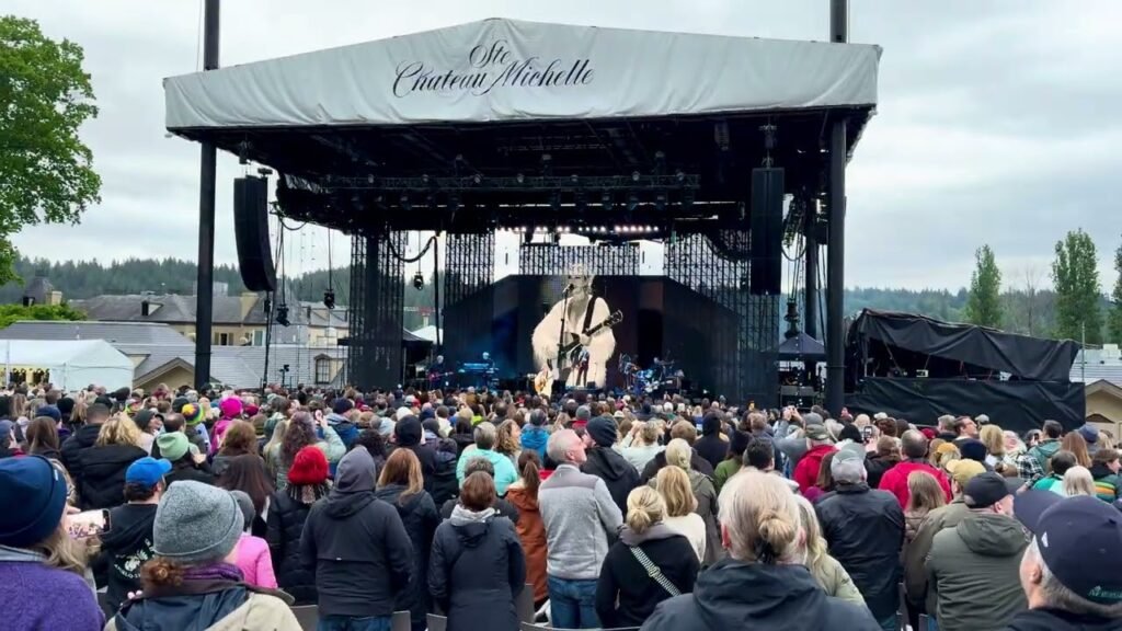 A packed audience at a live outdoor concert under a Creston Nichols stage tent in the Pacific Northwest.
