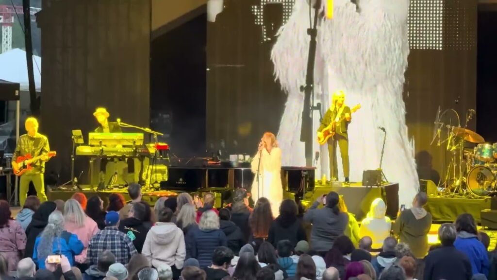 A vibrant outdoor music performance with a large audience enjoying the stage.