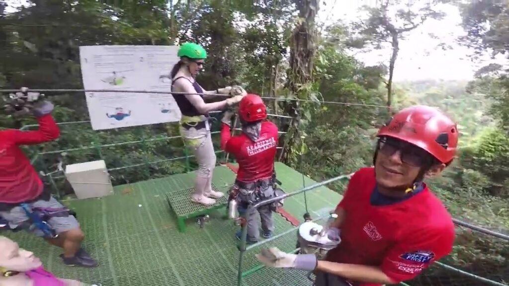 Travelers enjoy a ziplining excursion on a suspended platform surrounded by tropical foliage. People in safety gear prepare to launch into the jungle canopy.