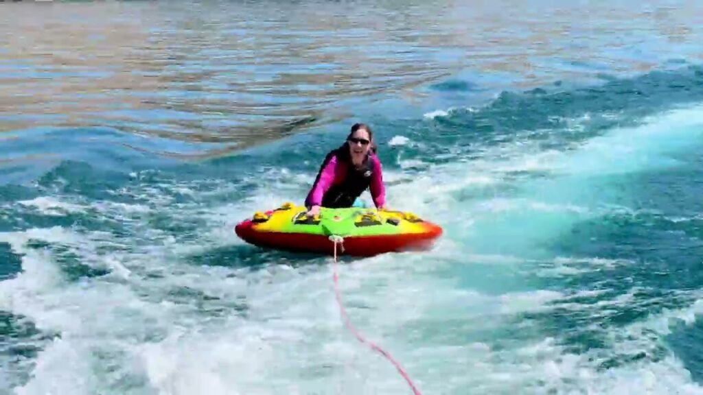 A person is sliding on a yellow and red float attached to a rope on the water.