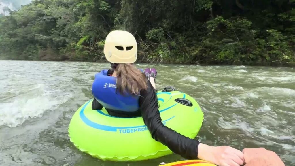 A person in a wetsuit and helmet white water rafting.