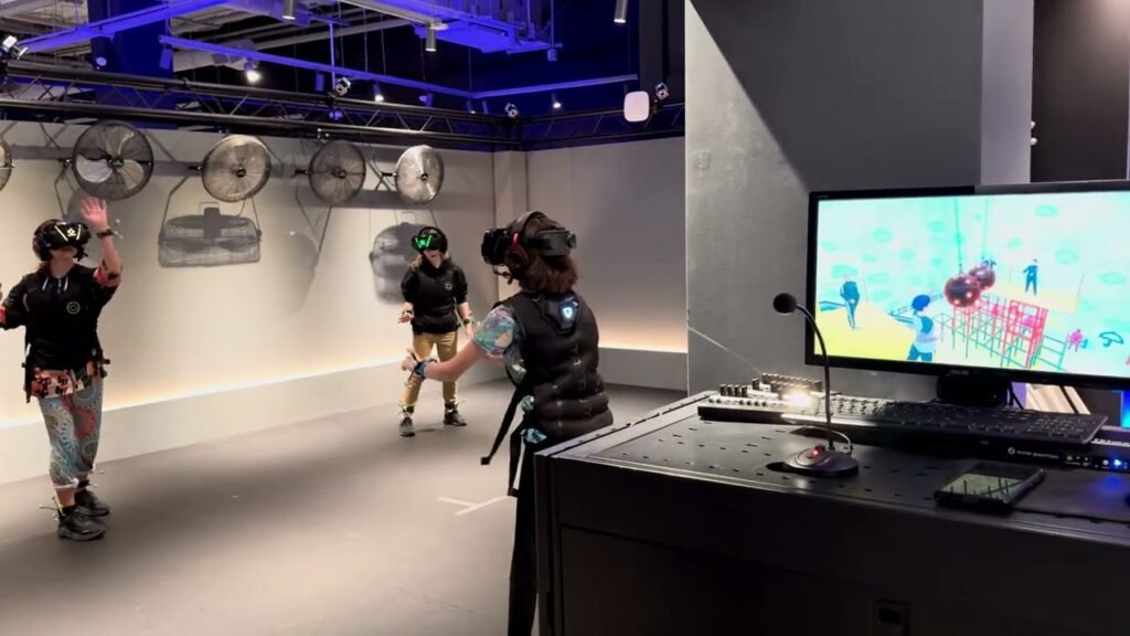 People use VR headsets and controllers in a room with visual mapping on screen.